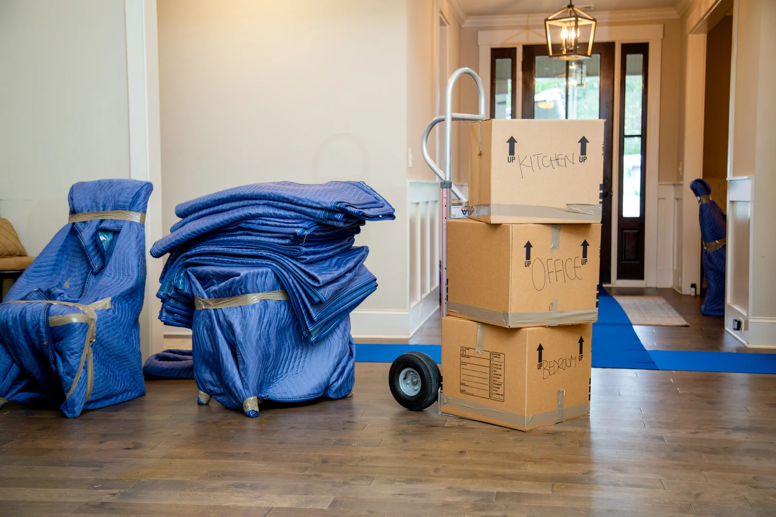 Fragile items covered in protective cushioning and boxes placed on a dolly to prevent damage during movement.