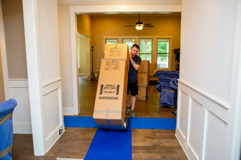 Professional mover carrying heavy stacked boxes during a residential move.