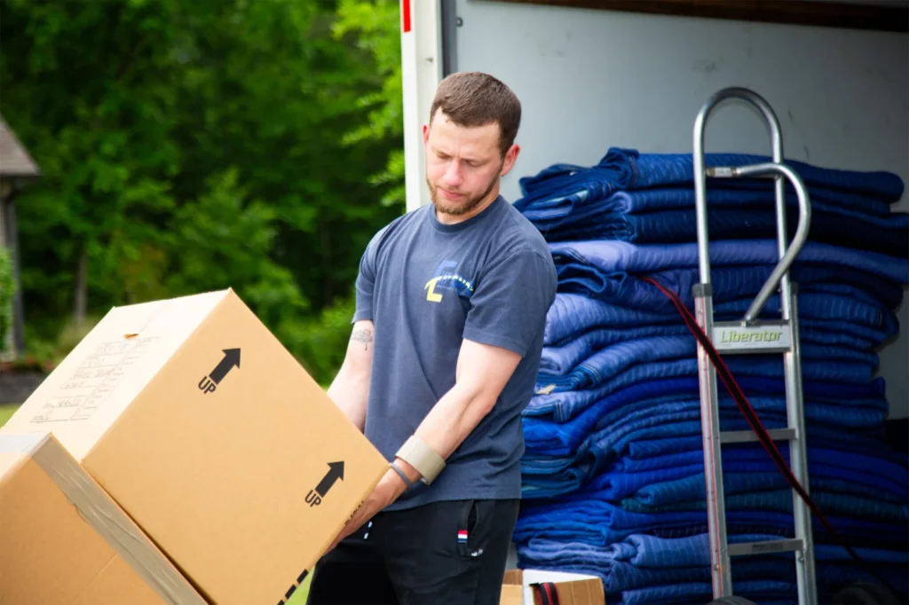Professional mover carrying heavy stacked boxes during a residential move.