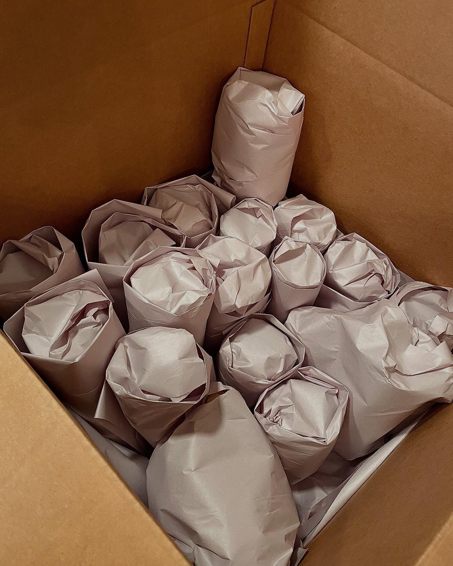 Fragile items wrapped in packing paper and carefully placed inside a cardboard moving box.