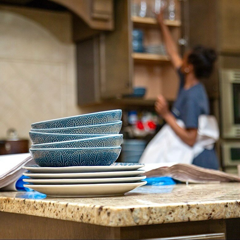 A professional mover carefully wrapping and packing dishes into a cardboard box during a move.