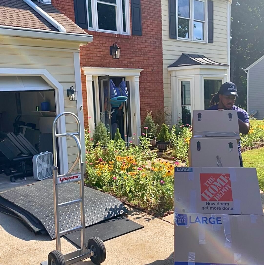 Professional mover carefully transporting stacked cardboard boxes during a residential move.