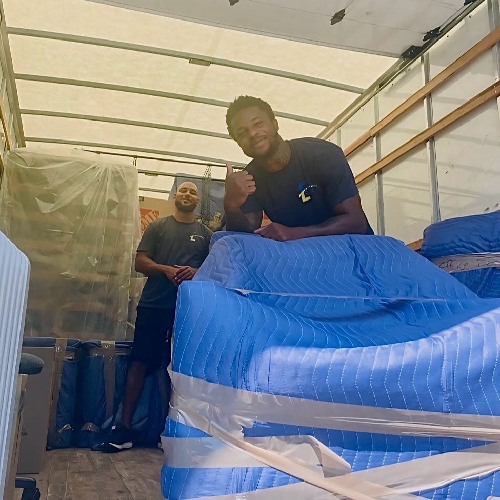 Two movers working together inside a loaded moving truck during relocation services.