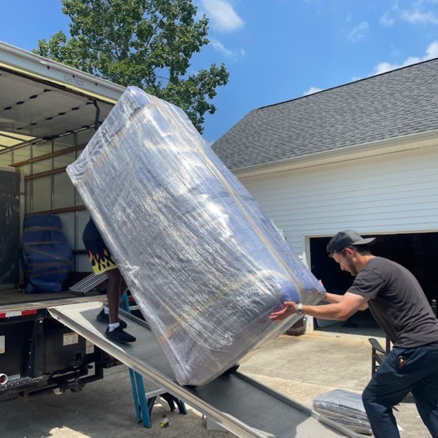 Professional mover transporting a specialty item wrapped in protective packing material.