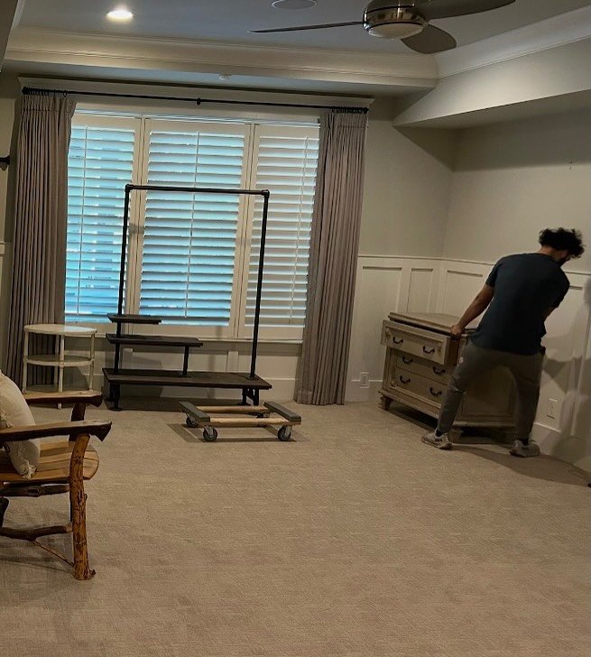 Mover carefully placing furniture in designated rooms of a new house after relocation.