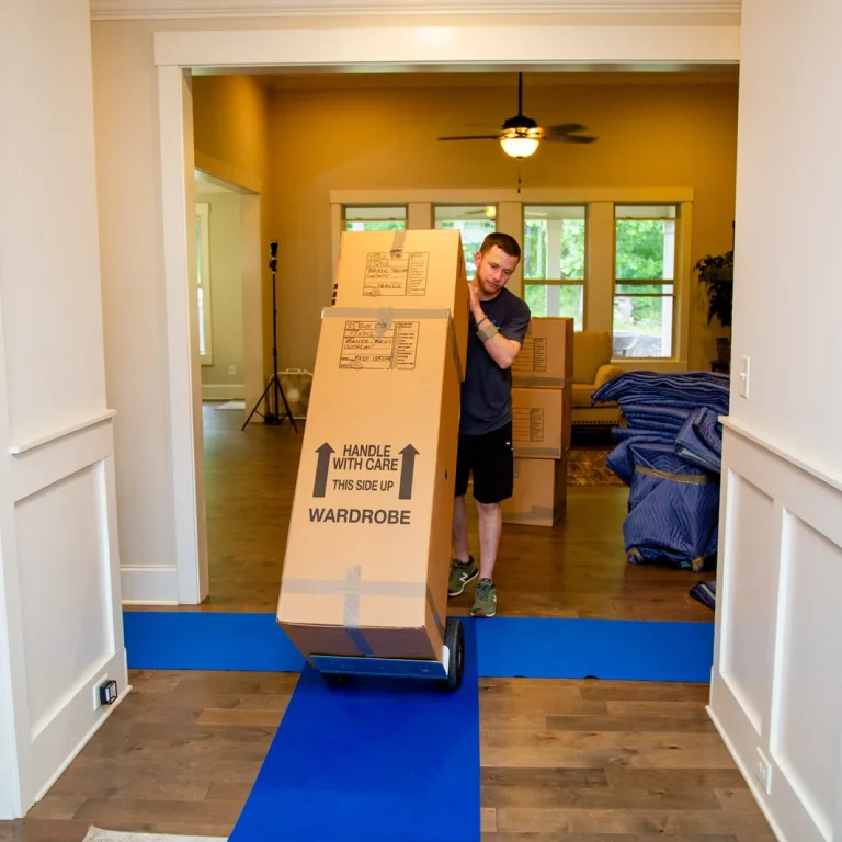 Professional mover carrying heavy stacked boxes during a residential move.